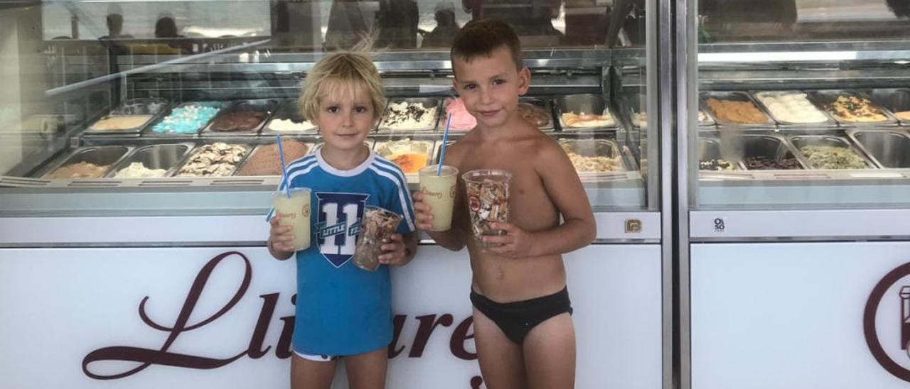 Dos niños posan con los vasos de colillas y los granizados.