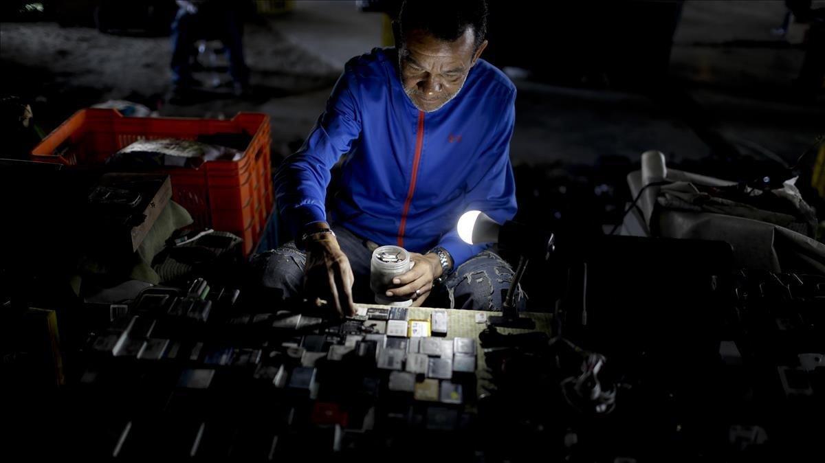 Un hombre coloca las baterías usadas en un intento de venderlas en un mercado bajo un puente vial en Caracas, Venezuela.