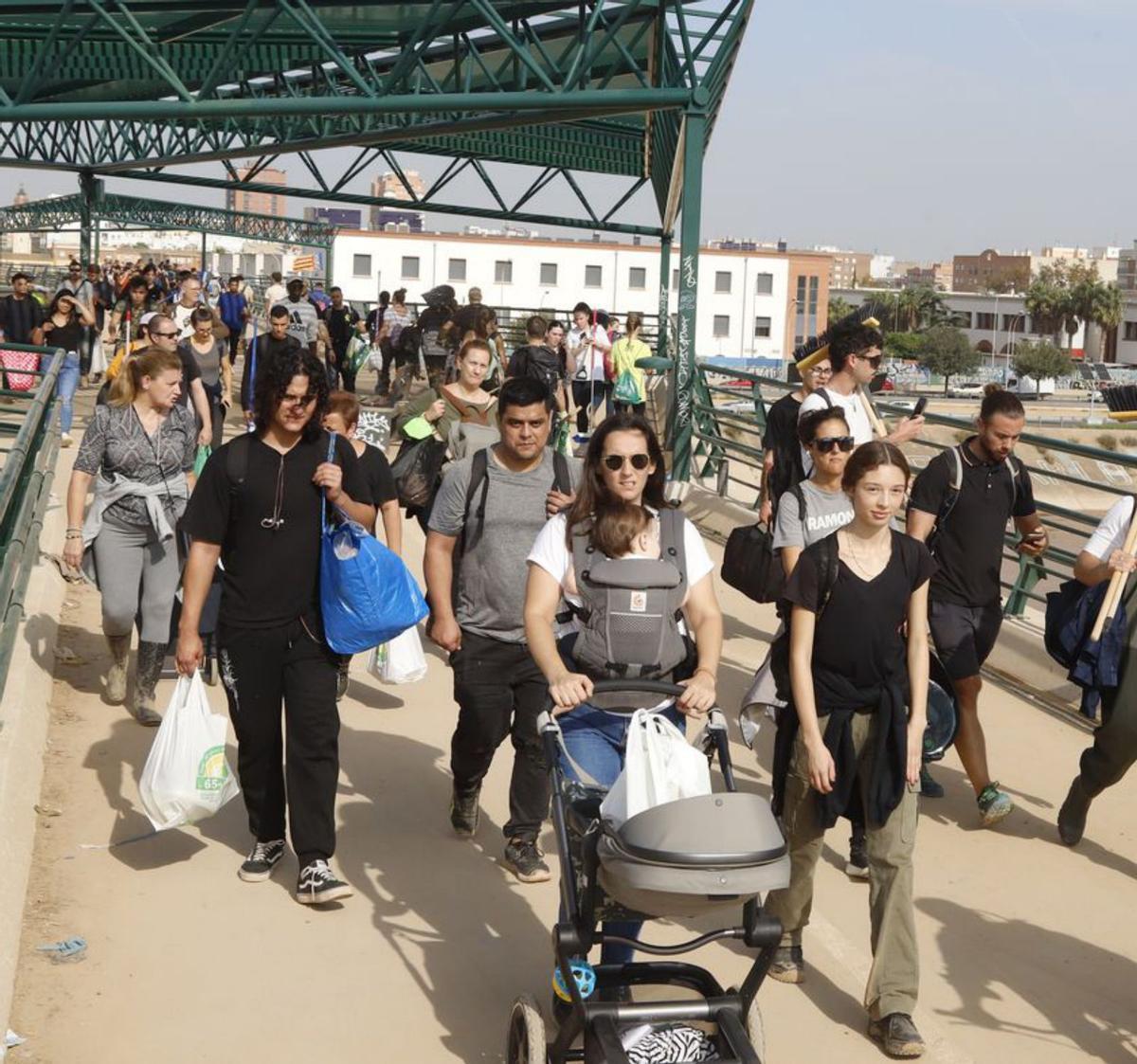 En el corazón de la dana | A LA IZQUIERDA, UN VEHÍCULO DE LA GUZMÁN EL BUENO RETIRA LODO Y ENSERES DE LAS CALLES DE ALGEMESÍ. A LA DERECHA, DECENAS DE JÓVENES CRUZAN EL LLAMADO PUENTE DE LA SOLIDARIDAD HACIA LAS LOCALIDADES AFECTADAS POR LA DANA.