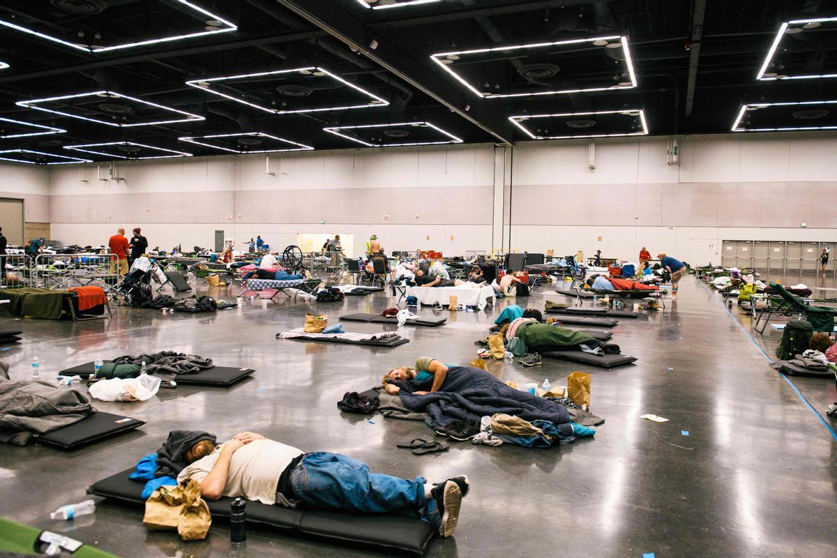 Un grupo de gente descansa y se refresca en el Centro de Convenciones de Oregon, en Portland, habilitado para que los ciudadanos puedan resguardarse del calor imperante en la zona.