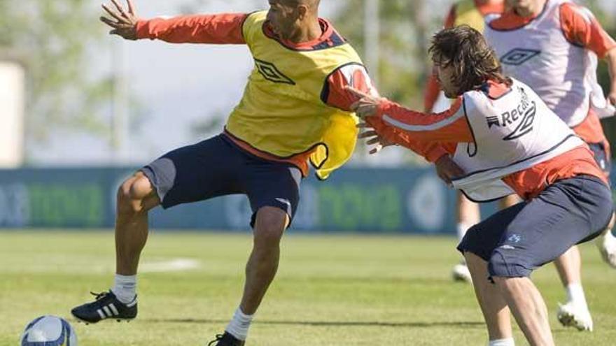 Dinei controla un balón ante la oposición de Jordi, que lo agarra, durante el entrenamiento de ayer en  A Madroa.