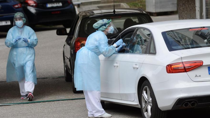 Una sanitaria realiza una prueba PCR a un paciente desde su coche en el Hospital Provincial de Pontevedra. // Rafa Vázquez