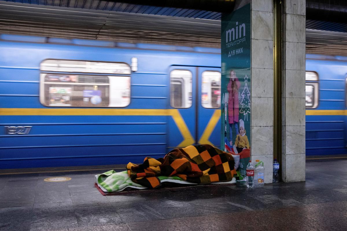 Una persona duerme en una estación de metro que sirve como refugio de posibles ataques aéreos, mientras continúa el ataque de Rusia contra Ucrania, en Kiev, Ucrania.