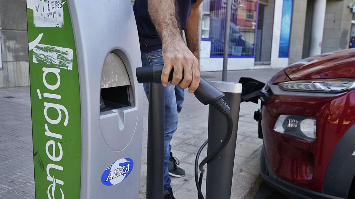 Un usuario conecta su coche al punto de recarga eléctrica de la plaza de Cristo Rey.