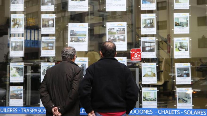 Varios clientes frente al escaparate de una inmobiliaria.