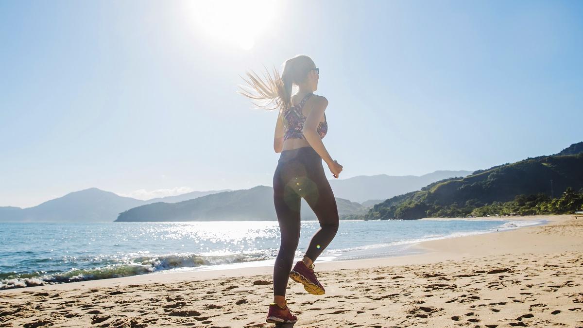 Una mujer practica 'running' descalza por la playa.