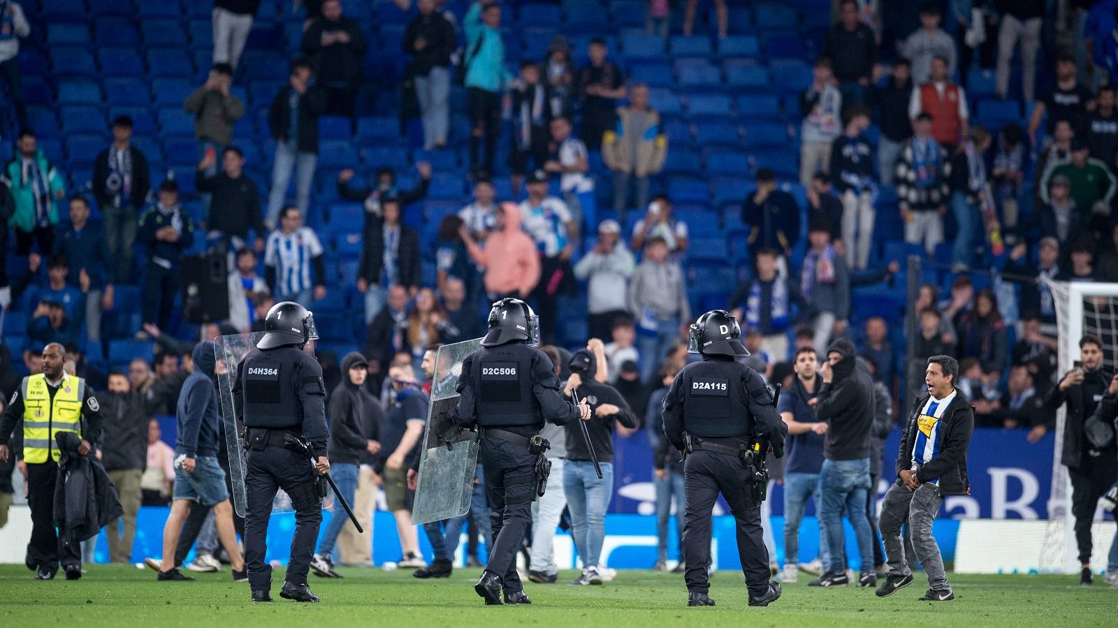 Los Mossos D'Esquadra intentan frenar la invasión de campo de los aficionados radicales del Espanyol.