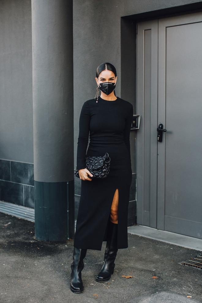 Look 'total black' con vestido de punto y botas altas visto en el 'street style' de Milán