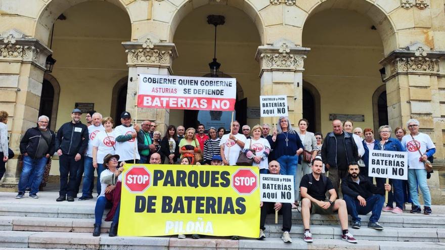 Vecinos con pancartas muestran su rechazo a la instalación de parques de baterías en el concejo ante el Ayuntamiento, durante la celebración del Pleno extraordinario. | A. G.-O.