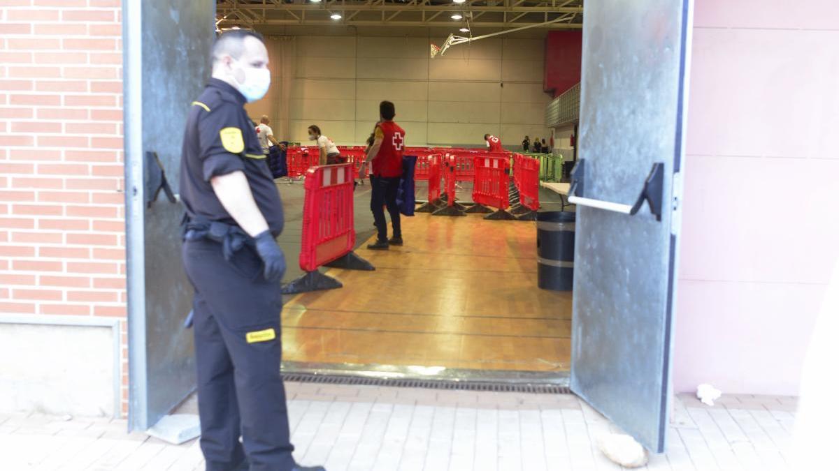 Un vigilante custodia la puerta del pabellón Cabezo Beaza donde los inmigrantes guardan cuarentena.