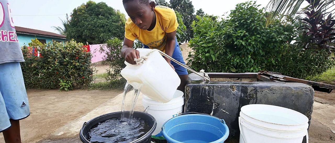 Un niño saca agua deun pozo situado en la comunidad Johnsonville,en Monrovia.