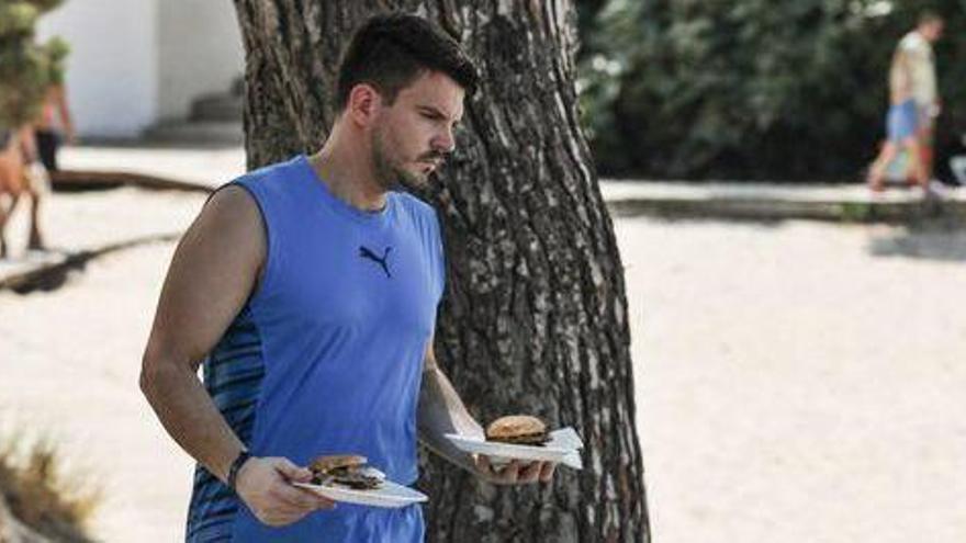 Un turista con un par de hamburguesas en Portinatx.