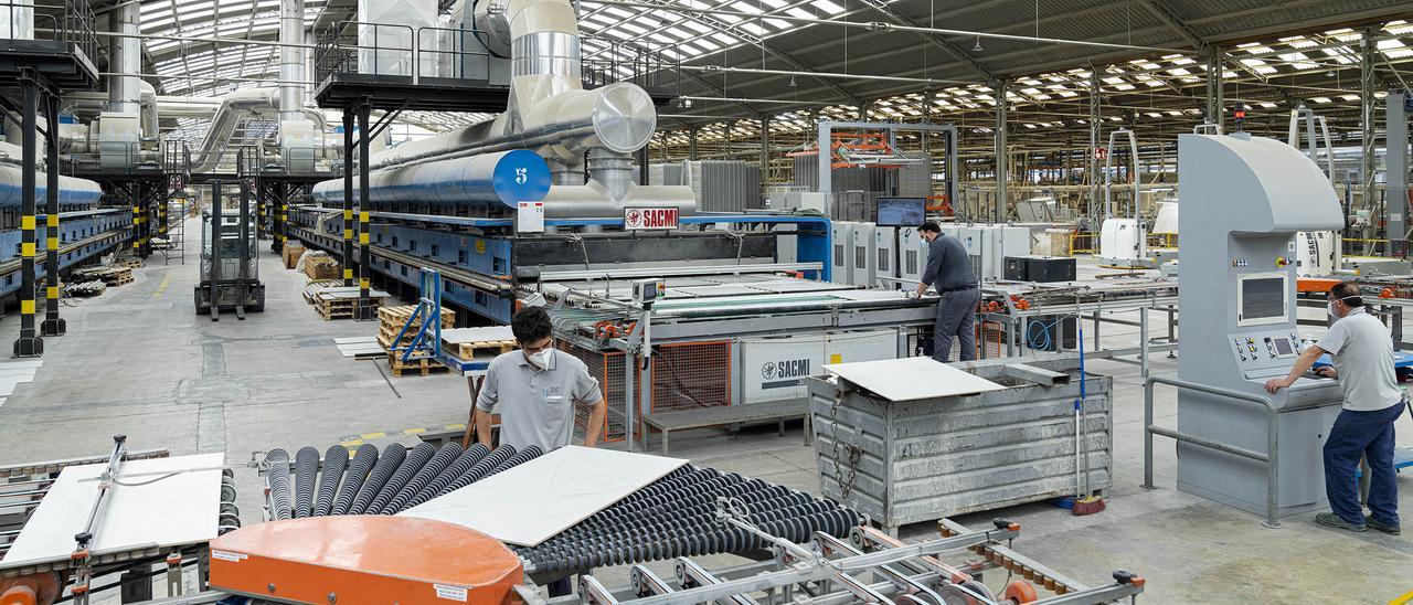 Operarios trabajan en el interior de una fábrica de azulejos.