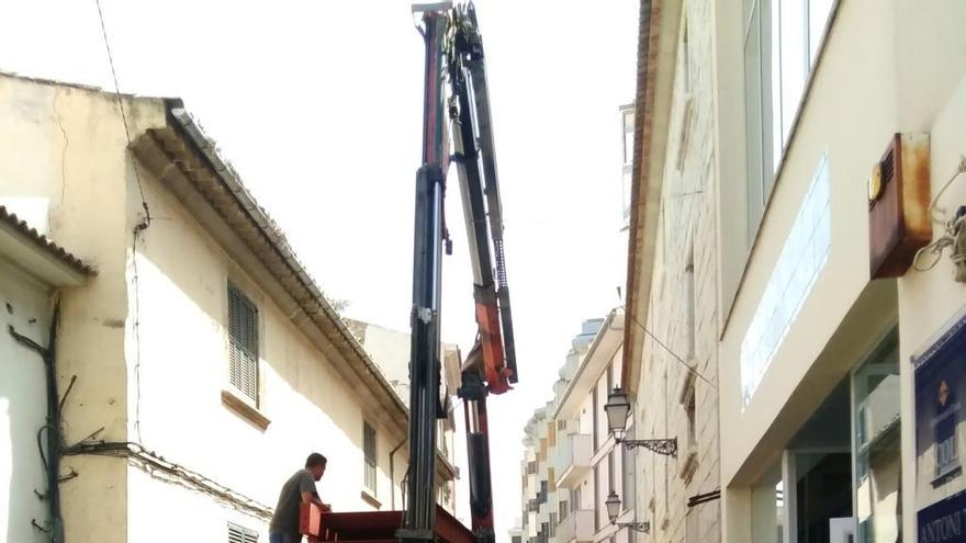 Varios operarios descargan las piezas de hierro de la nueva escalera con ayuda de una grúa