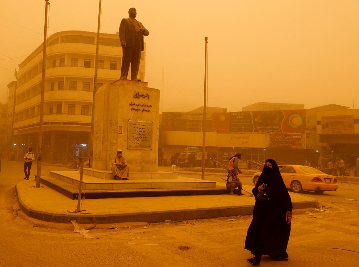 Una mujer pasa junto a la estatua del poeta iraquí Abdel Ghani Maarouf al Rusafi, durante la tormenta de arena en la ciudad de Bagdad