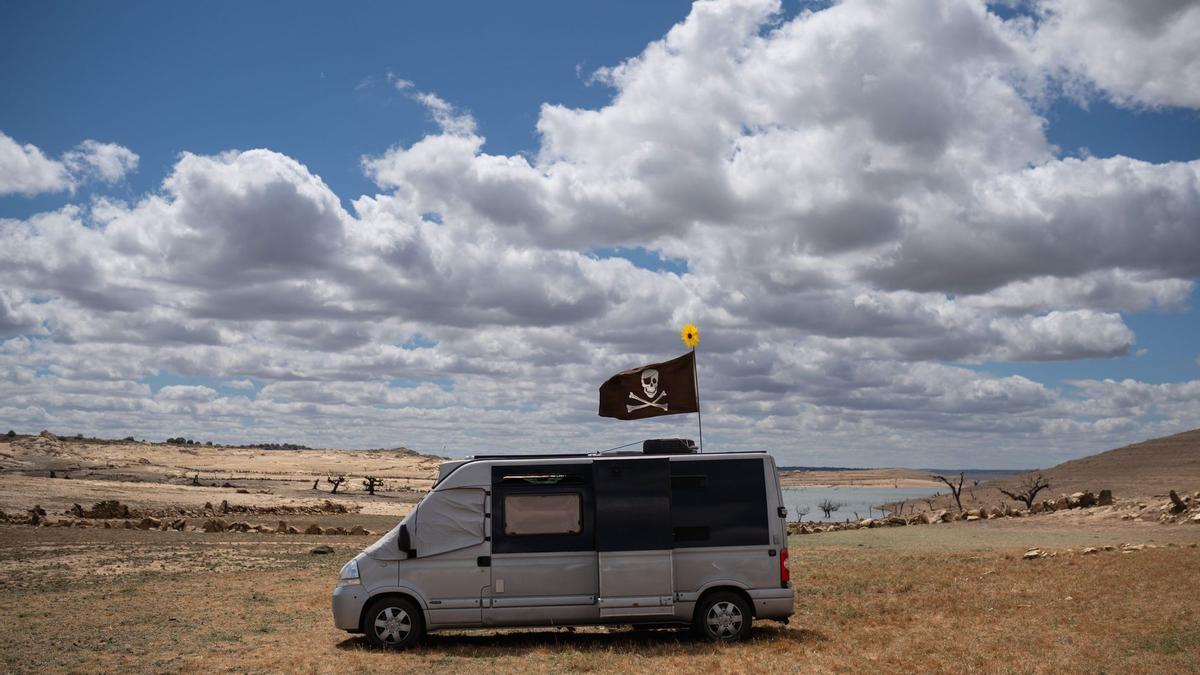 Una furgoneta camperizada con una bandera pirata junto al embalse de Almendra.