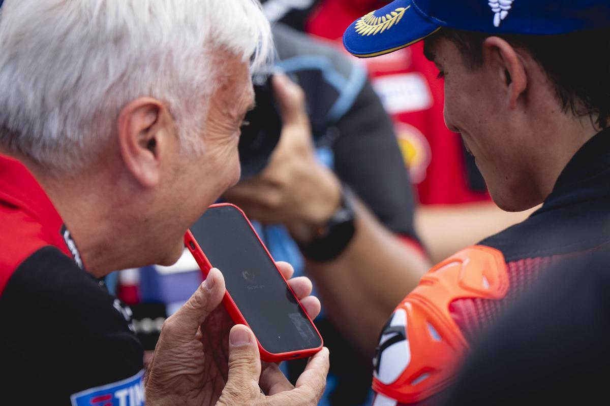 David Tardozzi le pasa su móvil a Marc Márquez, en el 'corralito' de Sachsenring, para que le felicite Gigi Dall'Igna.marc