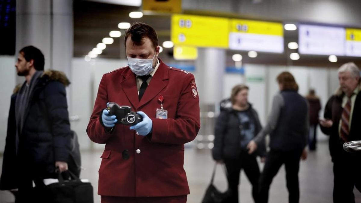 Un oficial de sanidad con un aparato para tomar la temperatura en el aeropuerto de Moscú.