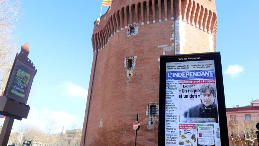 Un cartell amb la portada de L&#039;indepéndant on hi apareix Carles Puigdemont; al fons, el Castellet amb una senyera.