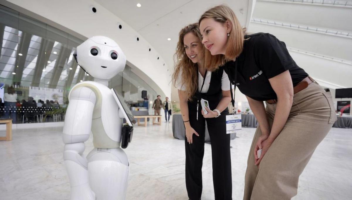 Dos asistentes, ayer, junto a uno de los robots de la exposición.