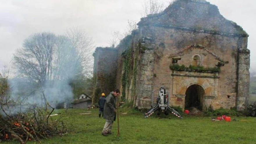 Un trabajador, quemando la maleza extraída del interior de la iglesia junto al edificio.