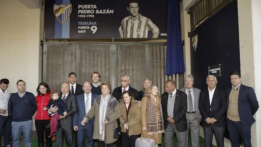 Foto de familia en la puerta 9 del estadio de La Rosaleda, con el reconocimiento a Pedro Bazán sobre ella.