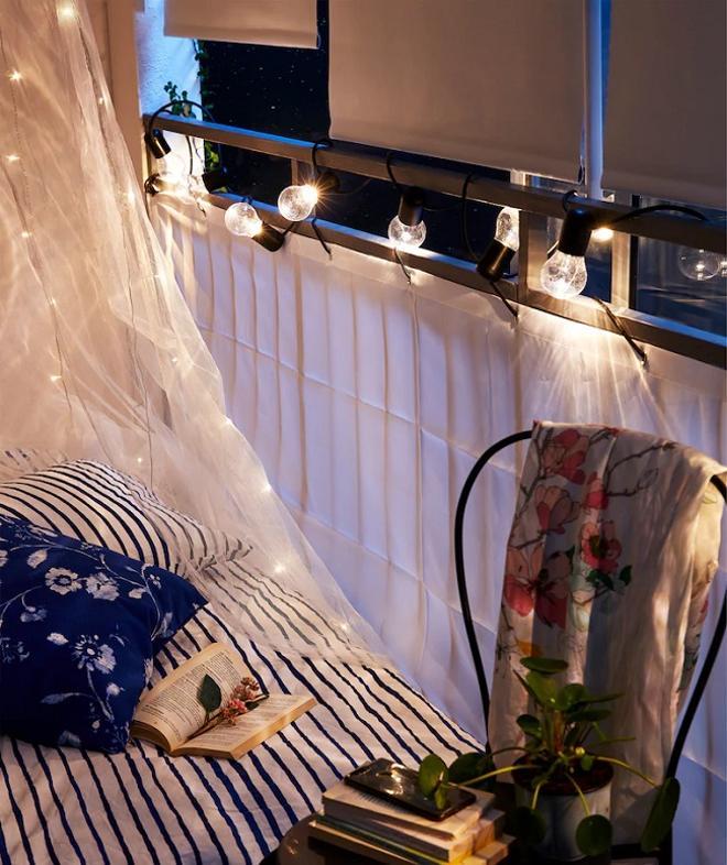 Guirnalda de luces y cojines de Ikea en el balcón para un ambiente acogedor
