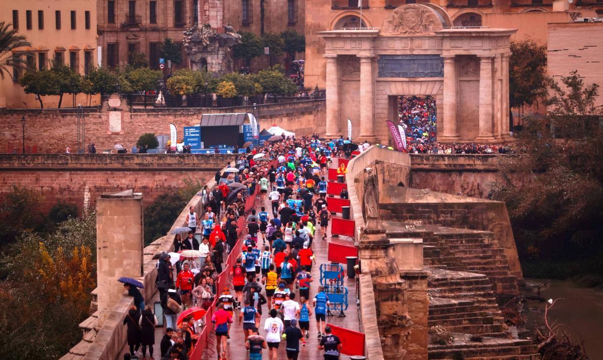 Centenares de atletas atraviesan el Puente Romano y la Puerta del Puente en la pasada edición de la Media Maratón de Córdoba.