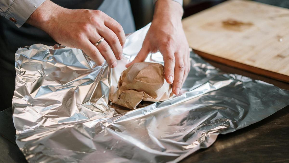 Una persona envuelve un alimento en papel de aluminio