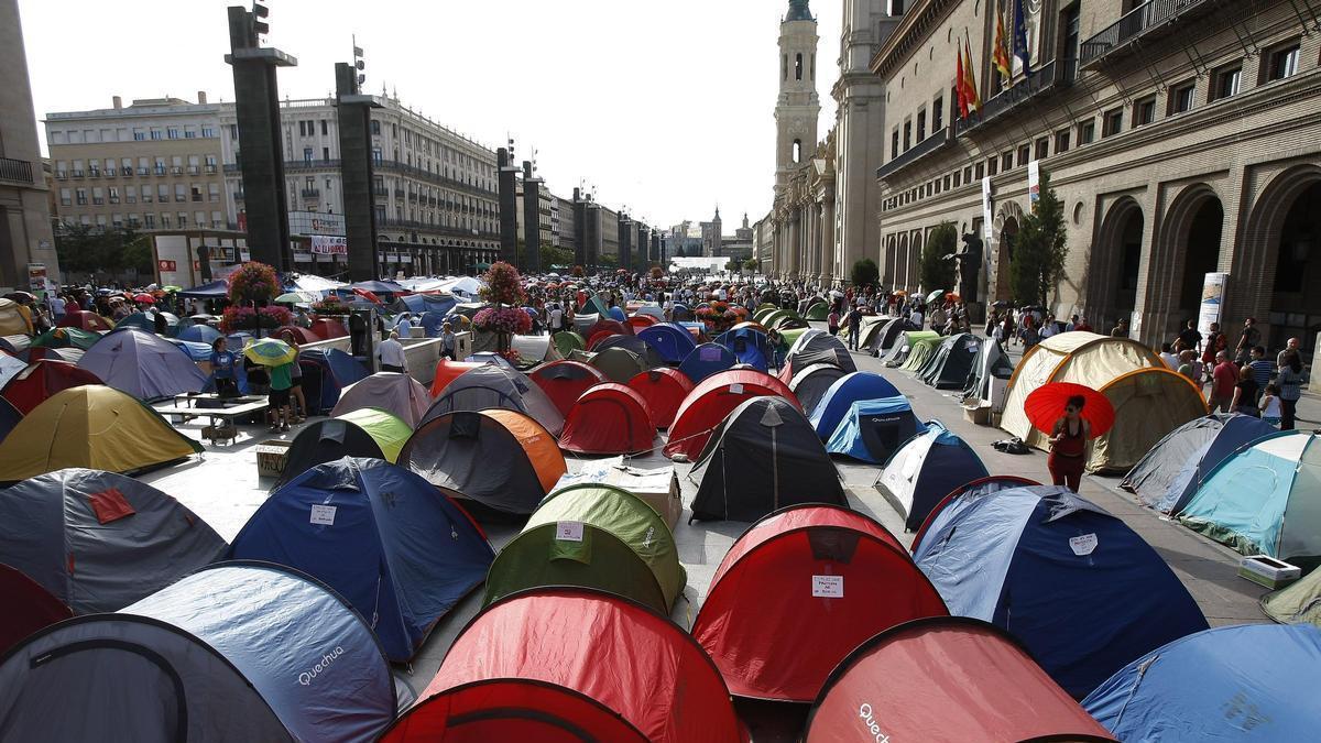 15 años del 15M, con una imagen de archivo de la acampada de los indignados en la plaza del Pilar de Zaragoza.