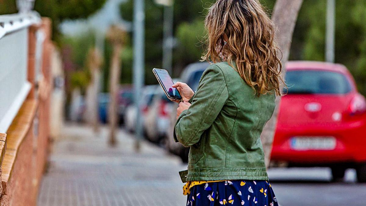 Una joven consulta su móvil mientras va por la calle.