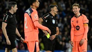 FC Portos Dutch forward #26 Luuk De Jong (R) is presented a yellow card by Spanish referee Jesus Gil during the Spanish league football match between Real Sociedad and FC Barcelona at Anoeta Stadium in San Sebastian on January 18, 2026. (Photo by ANDER GILLENEA / AFP)