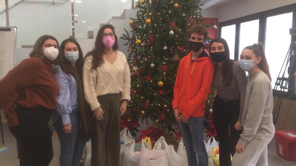 Alumnos del CEU posan con algunos de los alimentos recogidos para Cáritas.