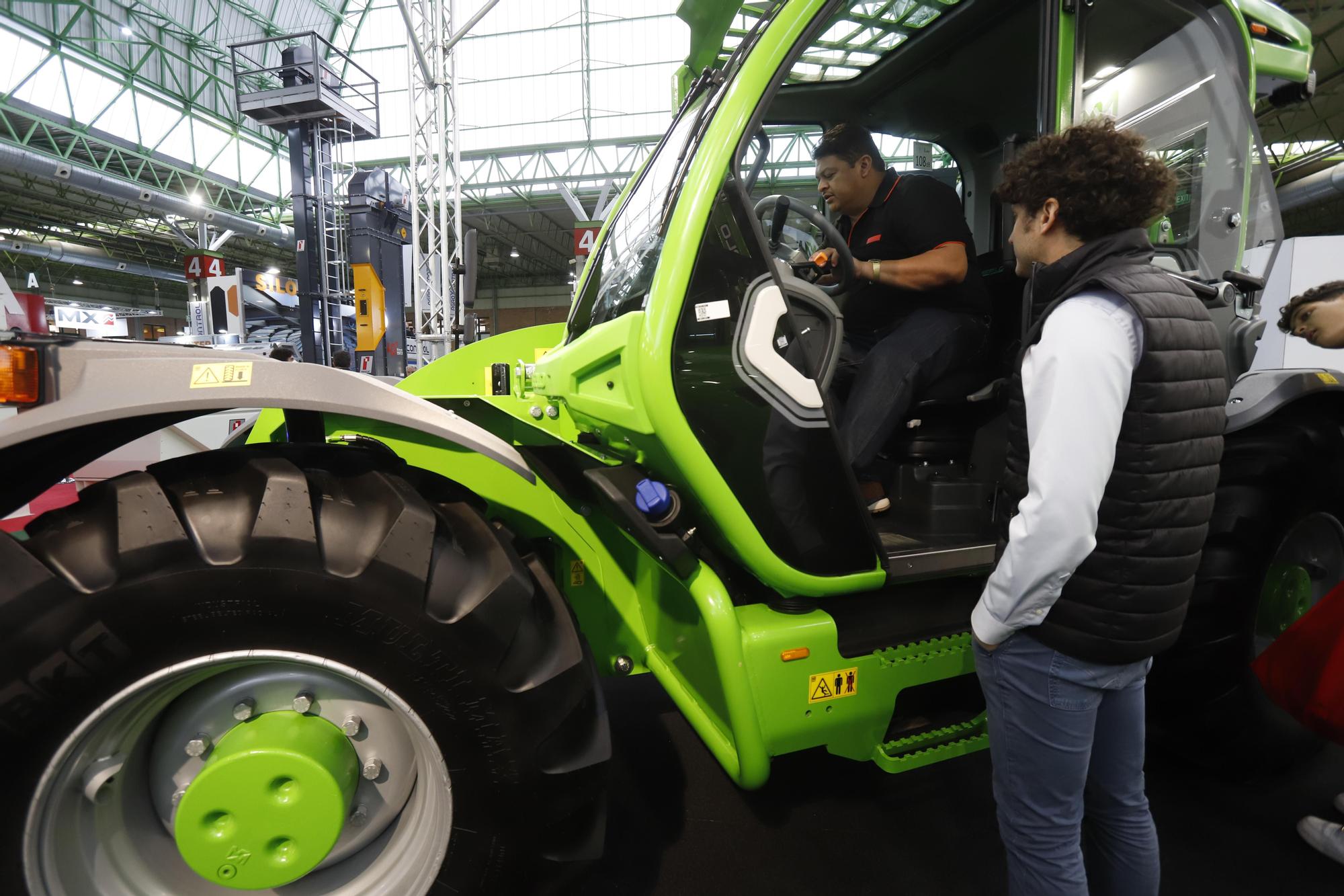 Un visitante se sube a la cabina de un tractor para ver su interior.