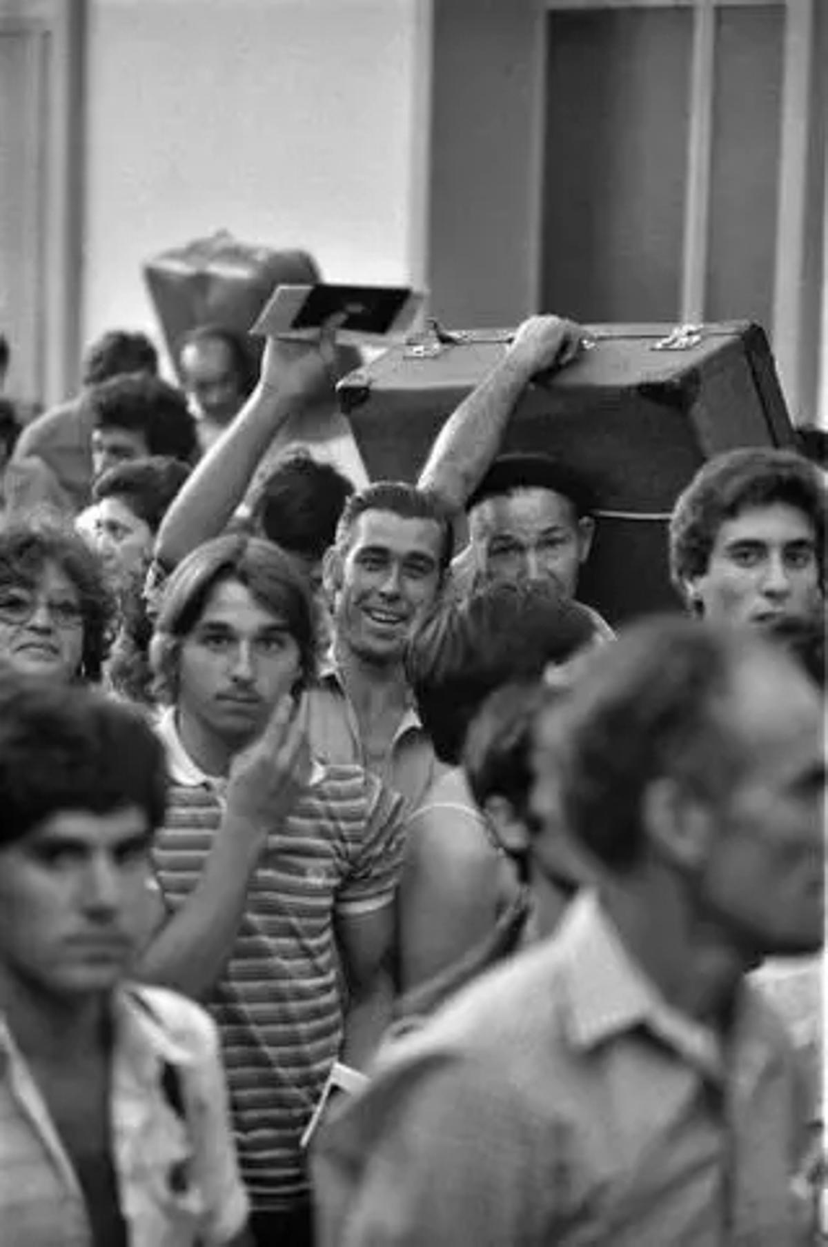 Un grupo de hombres y mujeres con los papeles listos y cargando maletas al inicio del camino.
