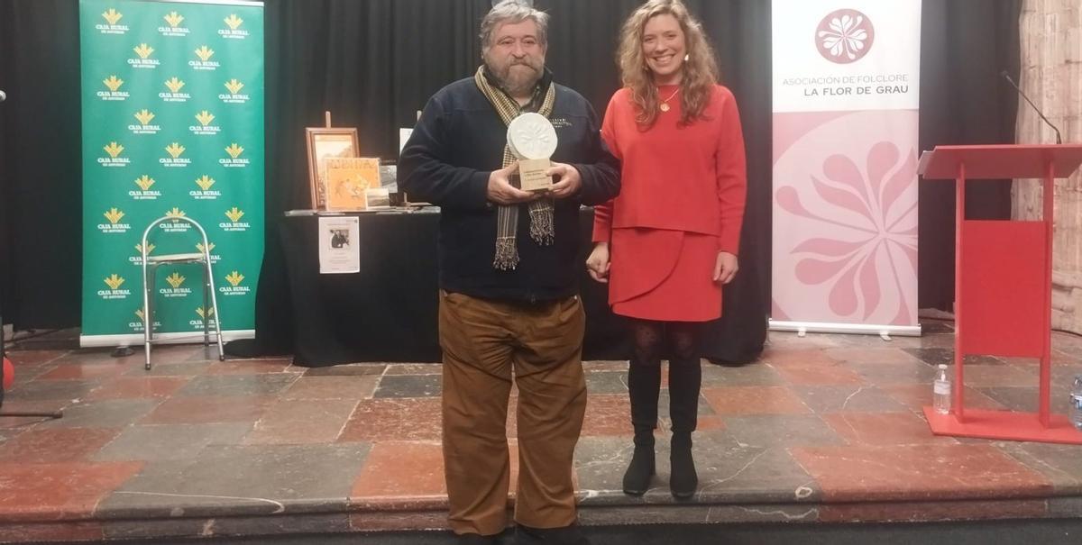 Lisardo Lombardía sostiene el premio junto a la presidenta de la Asociación de Folclore La Flor de Grau, Marta Canteli. | SARA ARIAS