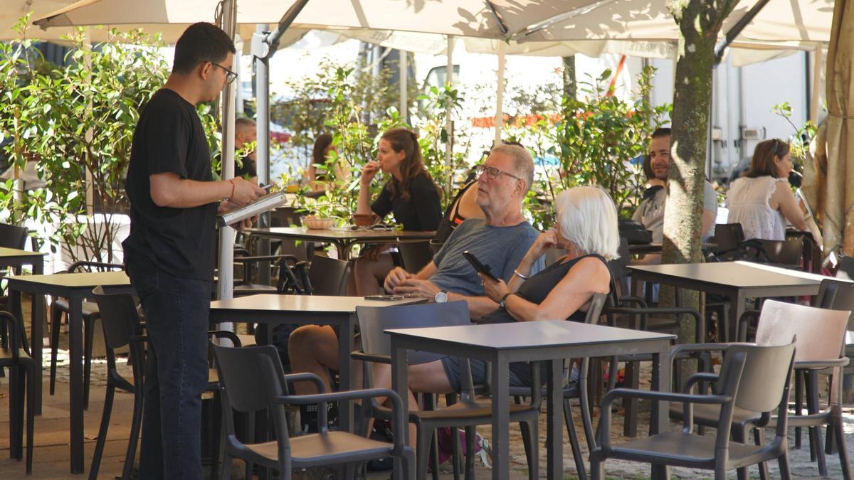 Un camarero tomando nota a unos clientes en una terraza de Santiago