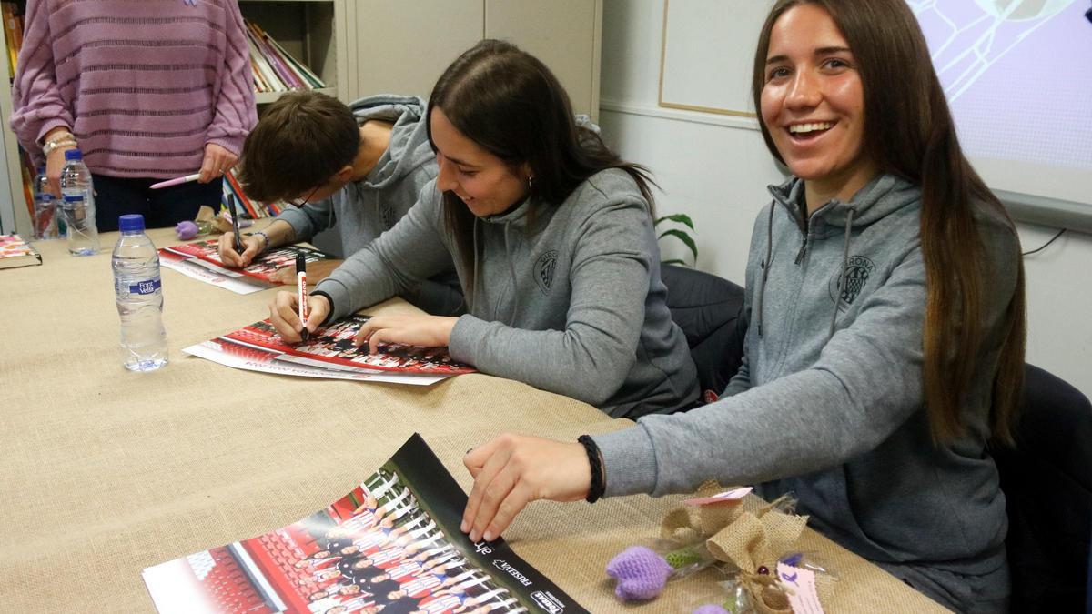 Les tres jugadores del Girona FC signant pòsters de l'equip després de la xerrada al centre de justícia juvenil de Montilivi aquest 8-M.