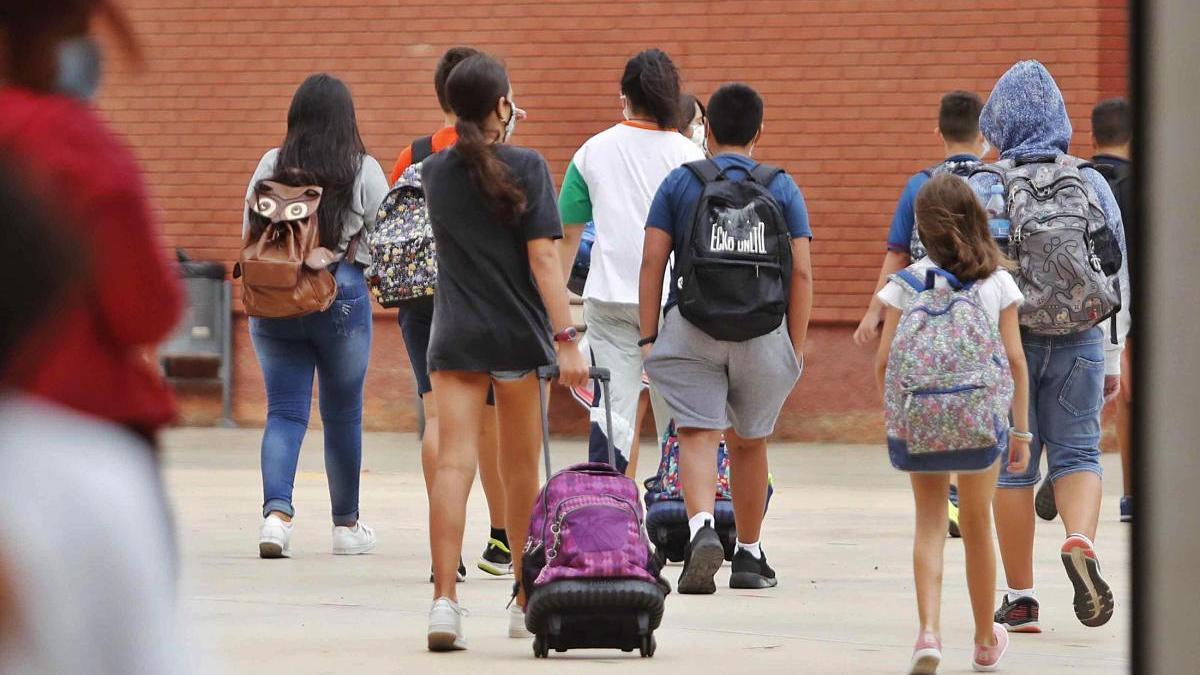 Un grupo de escolares de València accede  a su centro, con sus mochilas y protegidos con mascarillas.