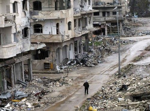 Un miembro del Ejército Sirio Libre camina por una calle llena de escombros