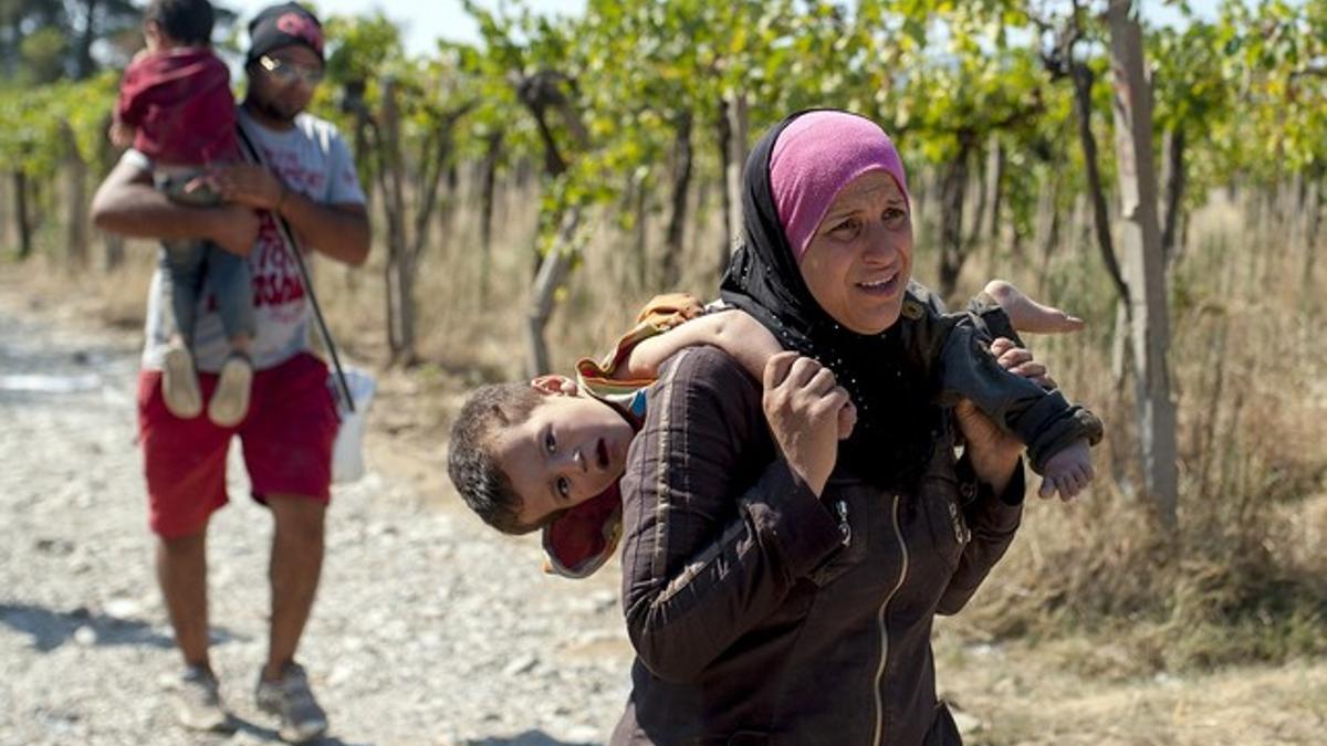 Una mujer carga con su hijo en Macedonia, este viernes.