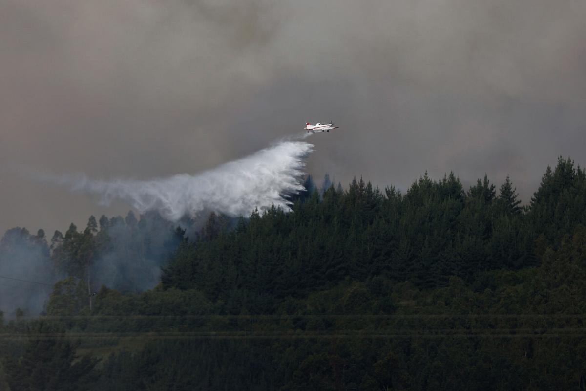 Un avión de extinción de incendios arroja agua en la zona de incendios forestales en Concepción, Chile, el 18 de enero de 2026.