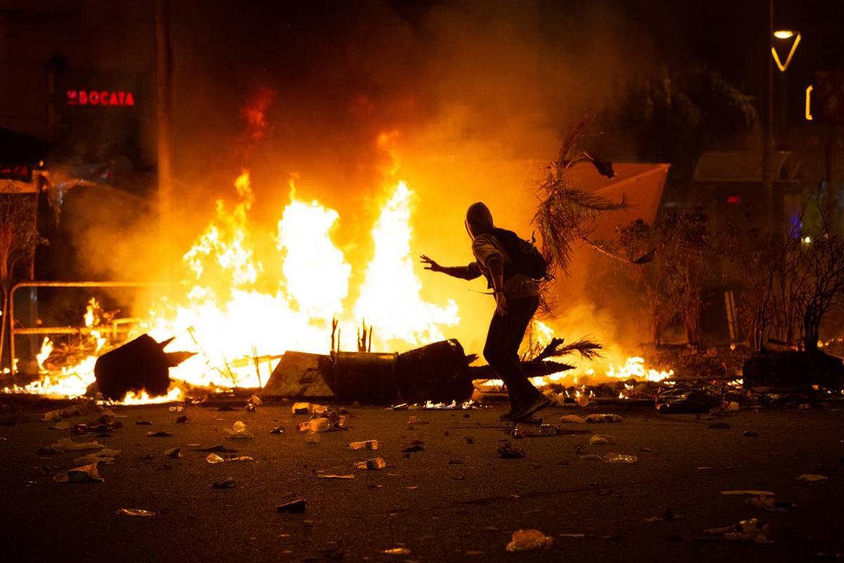 18/10/2019 Un manifestantes corre frente al fuego durante los disturbios en la Plaza de Urquinaona, en Barcelona a 18 de octubre de 2019.