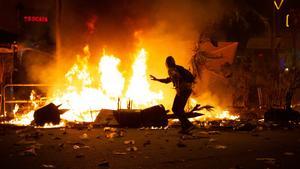 18/10/2019 Un manifestantes corre frente al fuego durante los disturbios en la Plaza de Urquinaona, en Barcelona a 18 de octubre de 2019.