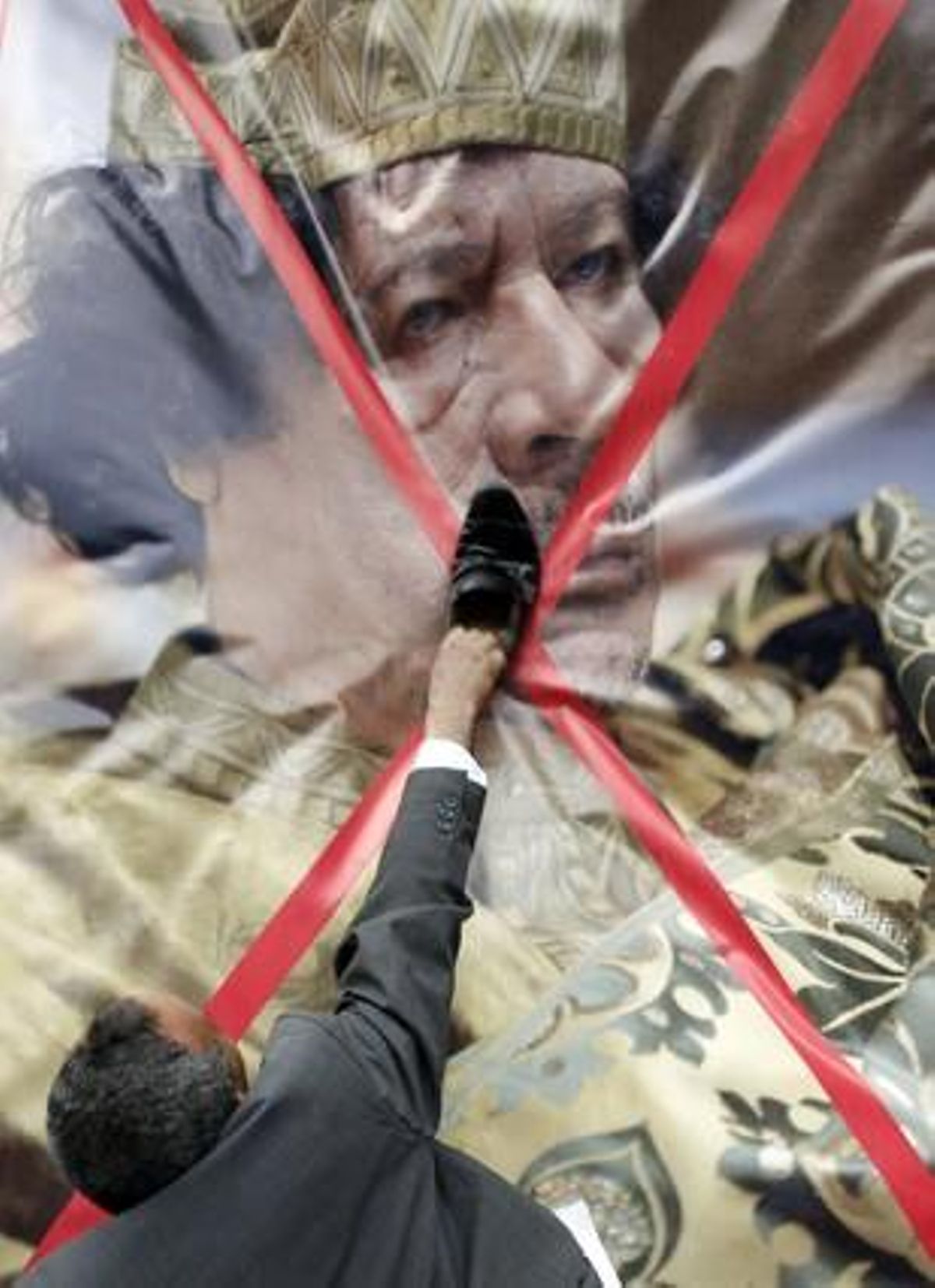 Un manifestant libi utilitza una sabata per picar la imatge ratllada del líder libi, Gaddafi, durant una manifestació davant de l’Ambaixada de Líbia al Caire (Egipte).