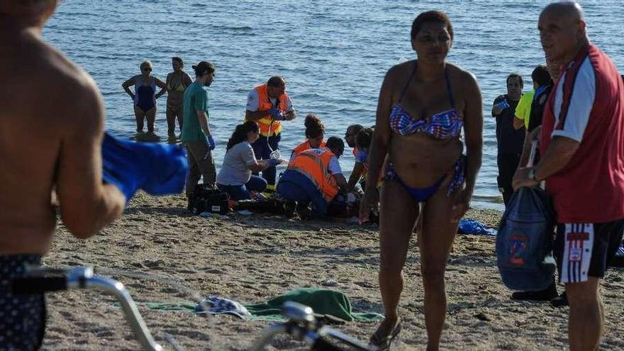 Al fondo, los sanitarios intentando reanimar a la bañista en la playa de A Concha, ayer por la tarde. // Iñaki Abella