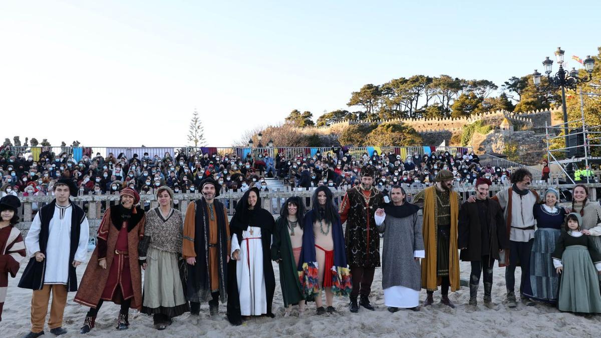 El elenco de la representación del desembarco de Pinzón en la playa de A Ribeira, con el público y la fortaleza de fondo.