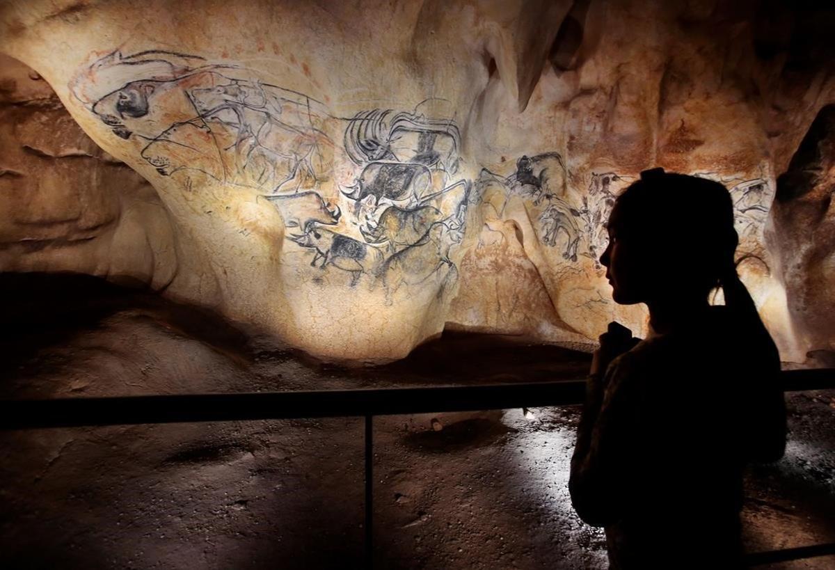 Una joven observa varios de los dibujos pintados en la gruta de Chauvet (Francia).