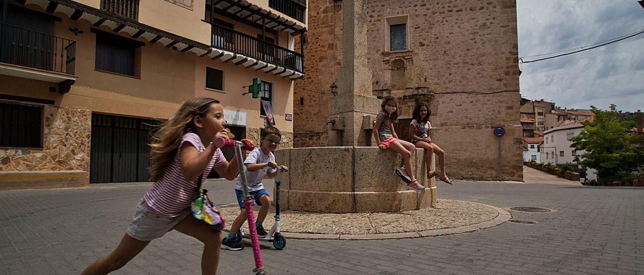 Una niña y un niño patinan ante la mirada de sus amigas en Vallanca (el Rincón de Ademuz).