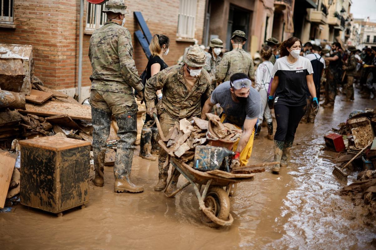 La fotografía que se ve a la derecha del Rey. Militares, vecinos y voluntarios quitan el lodo de las calles de Paiporta nueve días después de la dana.